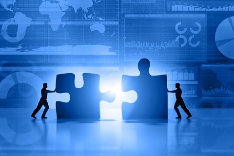 Silhouette of two business men moving and joining pieces of jigsaw puzzle on a business and stock market  blue background, with charts, diagrams, world maps and data arranged on grid and tables. World maps showing continents and countries with economy data and growth diagrams. Light glowing from the center. Copy space on bottom.